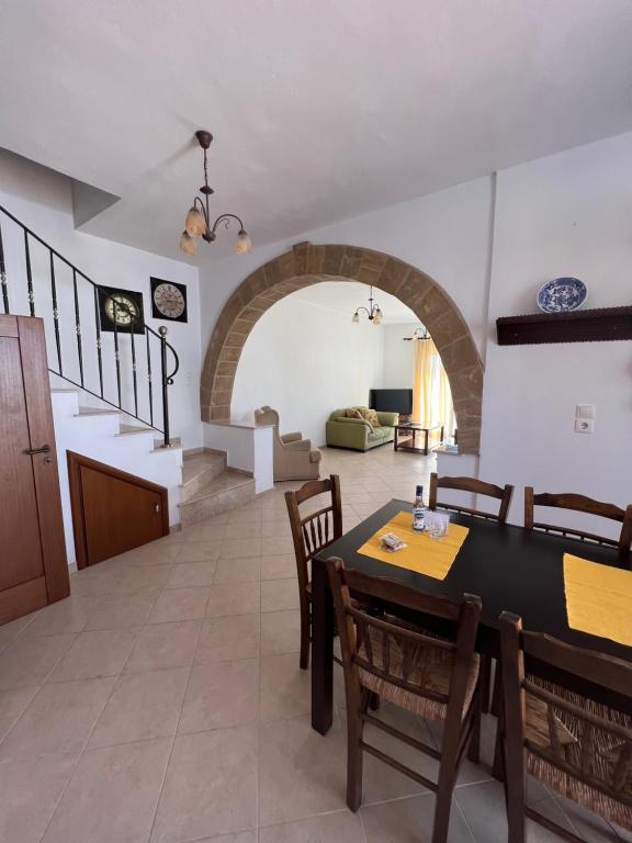 una sala da pranzo con tavolo, sedie e arco di Pounentis house a Messanagro