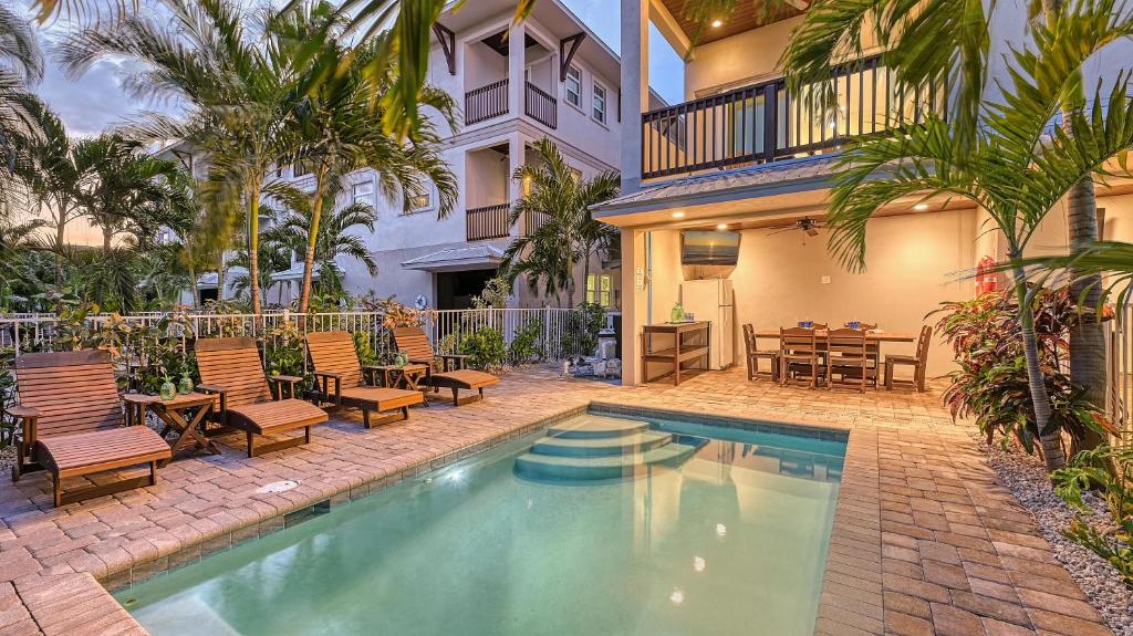 a swimming pool with chairs and a table and a house at Casa Antilles - 1036L in Siesta Key