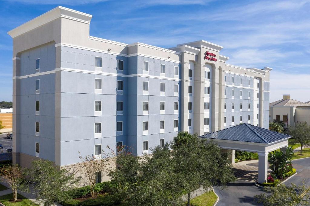 a large white building with a red sign on it at Hampton Inn & Suites Lakeland-South Polk Parkway in Lakeland