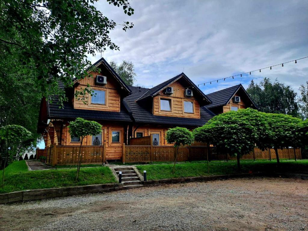 a wooden house with a black roof at Skansen Holiday in Cholerzyn