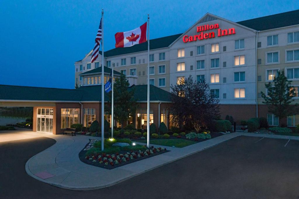 a hotel with flags in front of a building at Hilton Garden Inn Buffalo Airport in Cheektowaga
