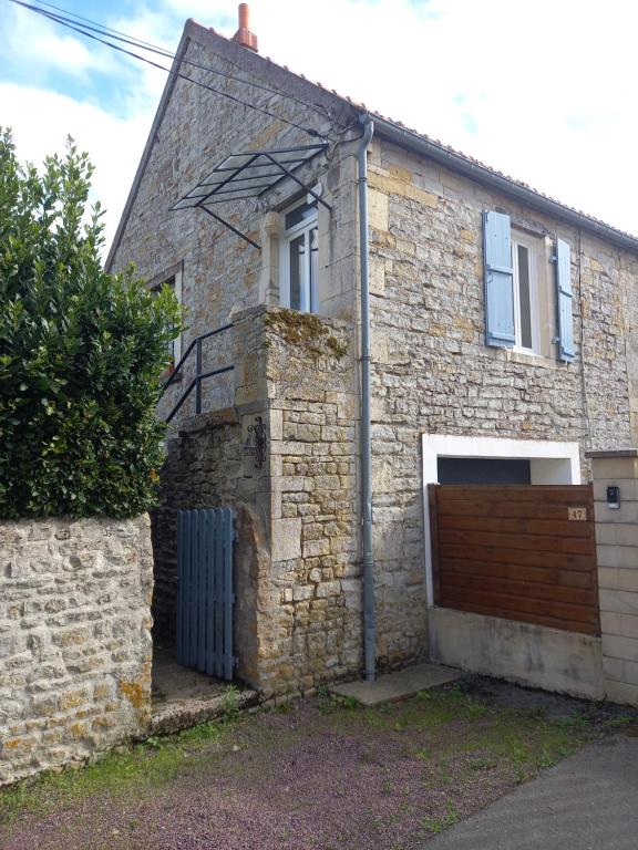 uma antiga casa de tijolos com uma porta de garagem de madeira em Maison Thalène em Longraye