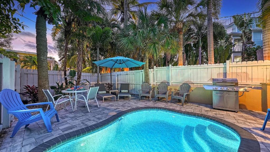 una piscina con sillas, una mesa y una sombrilla en Villa Castile - 5204, en Siesta Key