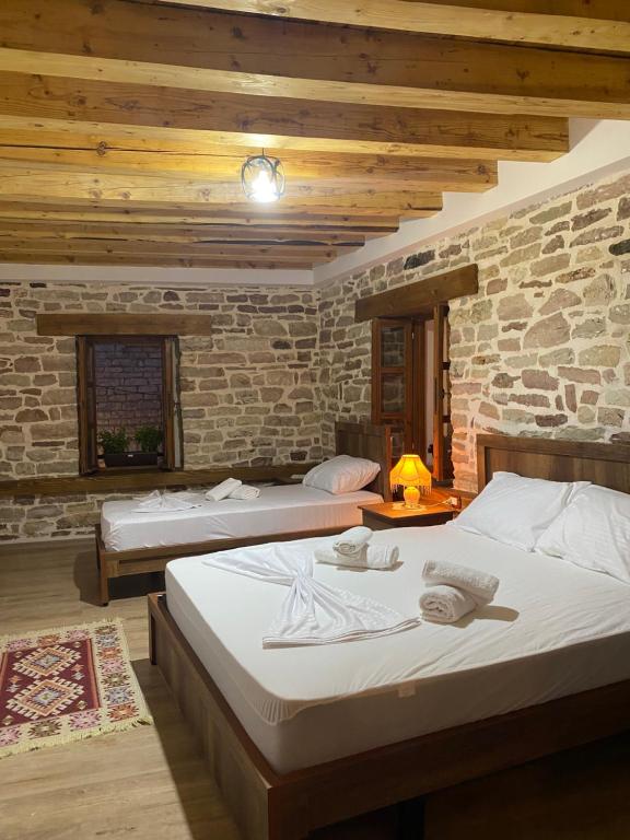 a bedroom with two beds and a stone wall at Guest House Ani-Rooms&Food in Old Bazaar,Gjirokaster in Gjirokastër