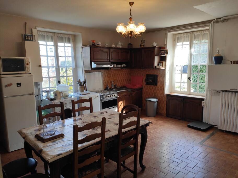 une cuisine avec une table en bois et des chaises ainsi qu'une salle à manger dans l'établissement Maison de Campagne en centre Bourg, à Renaison