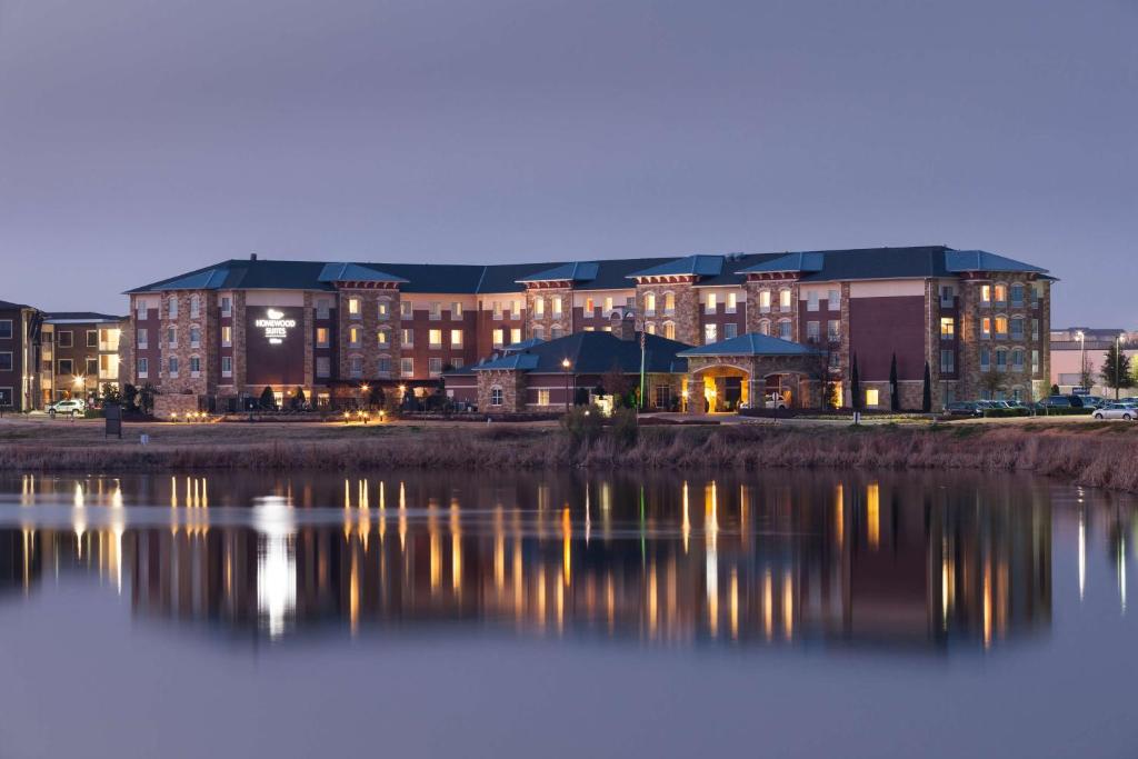 a large building with its reflection in the water at Homewood Suites Denton in Denton