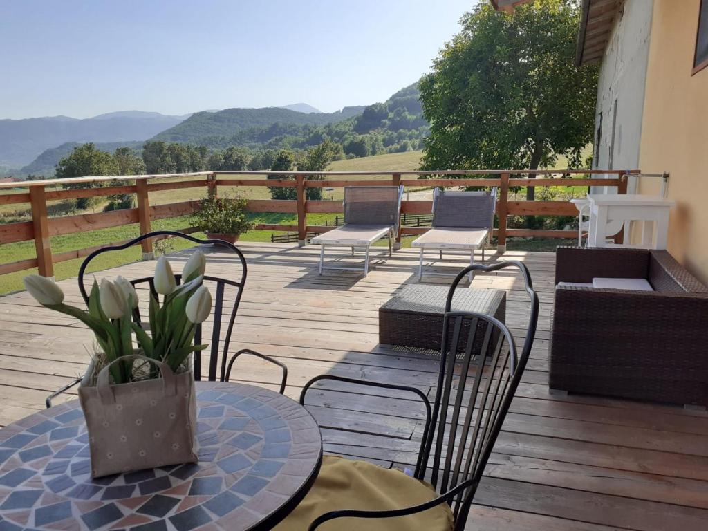 una terraza con sillas y una mesa con un jarrón en B&B Max & Lory, en Neviano degli Arduini