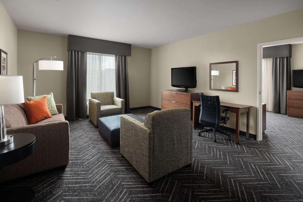 a hotel room with a couch and a desk with a television at Homewood Suites Springfield in Springfield