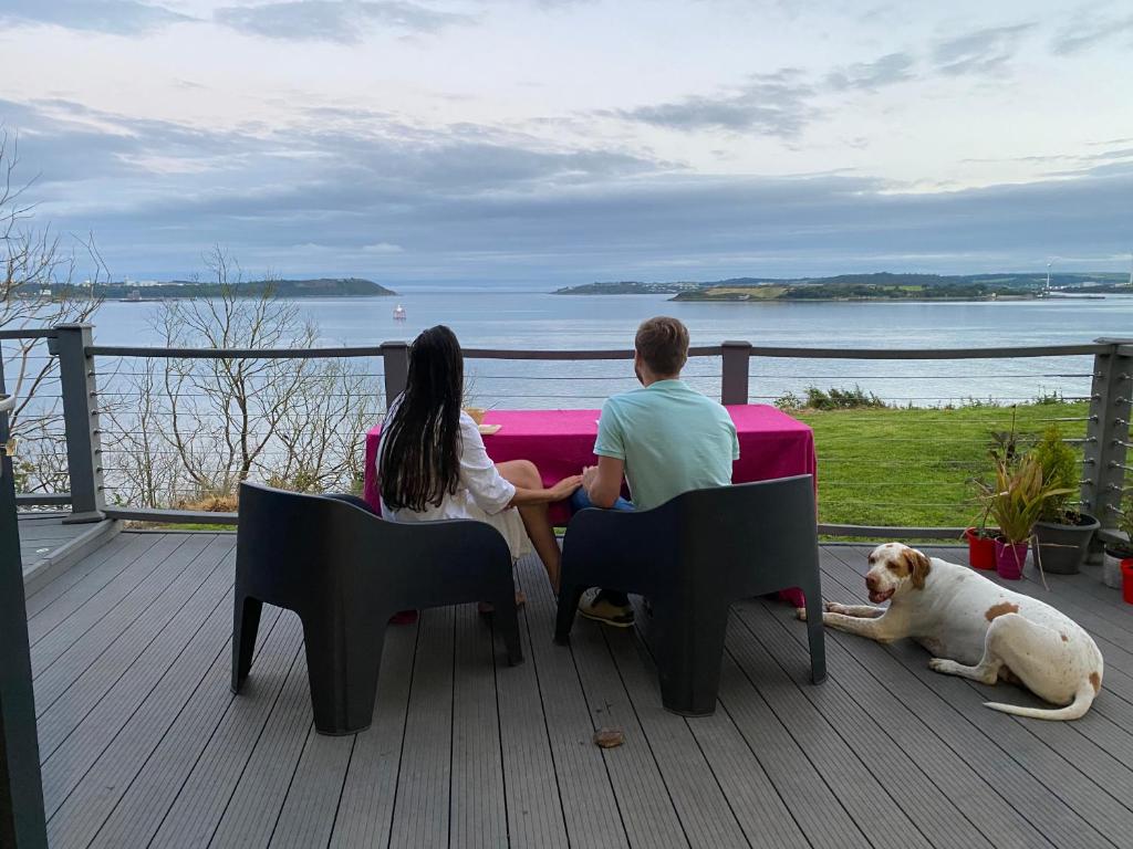a man and woman sitting on a deck with a dog at Newpark in Cobh