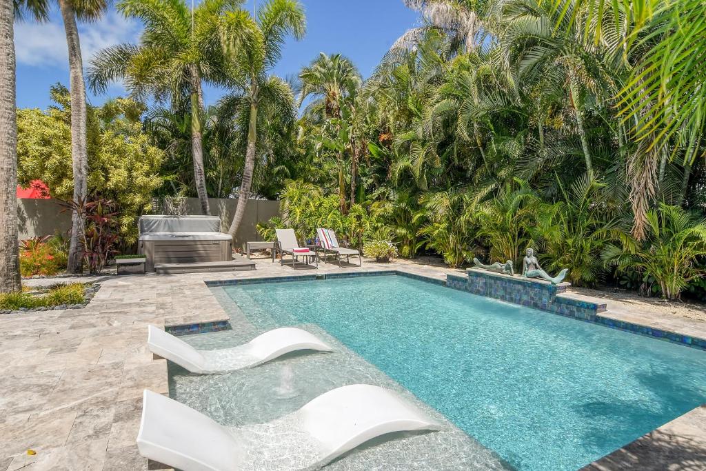 a swimming pool with white chairs and palm trees at Mermaids Oasis - 315 in Bailey Hall