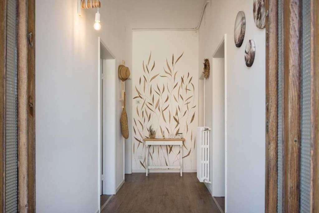 a hallway with a table and a wall with a plant mural at Perla Marina Appartamento in Rimini