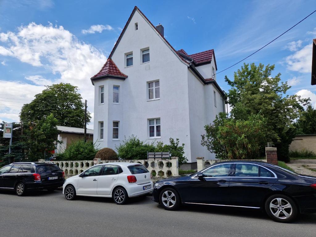 Tre macchine parcheggiate di fronte a una casa bianca di Unterkunft an der Karl-Marx Straße Leipzig a Lipsia