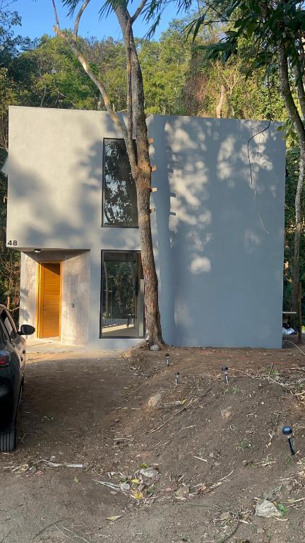 Una casa blanca con un árbol delante. en Monkey Lodge - Casa na Mata en Río de Janeiro