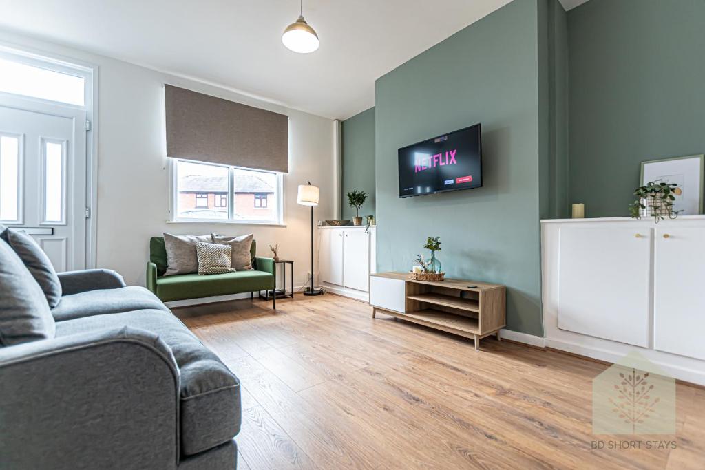 uma sala de estar com um sofá e uma televisão na parede em Cosy 3 Bedroom house in Wigan em Bickershaw