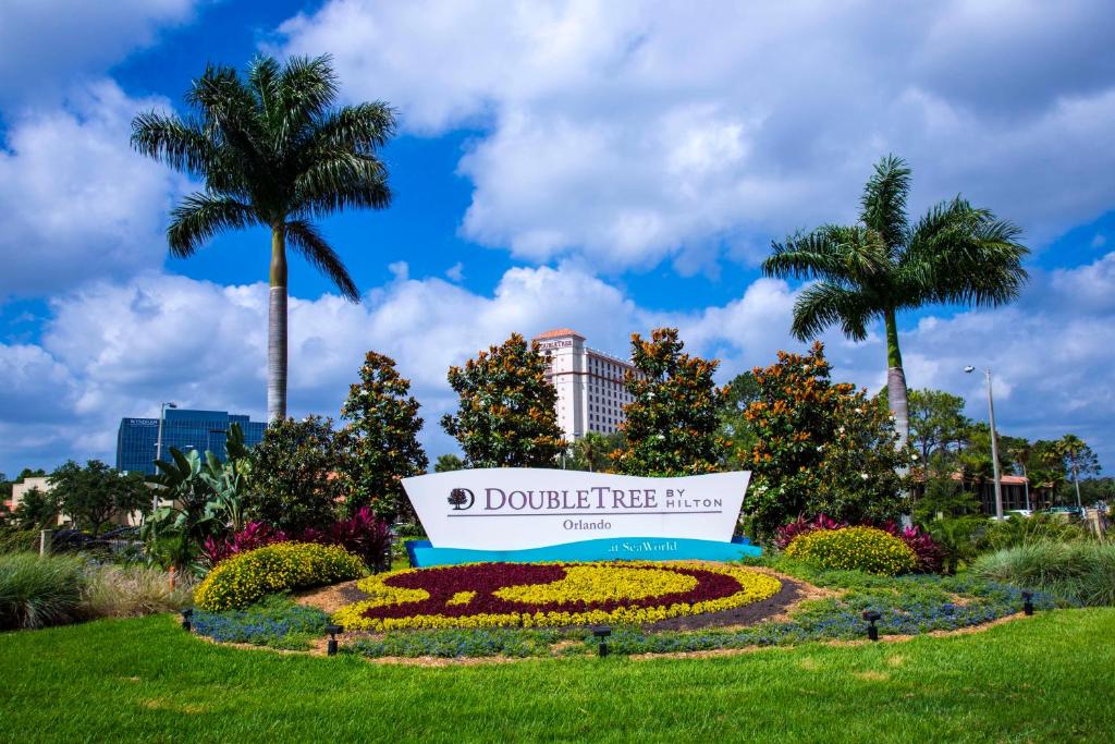 a sign in a park with flowers and palm trees at DoubleTree by Hilton Hotel Orlando at SeaWorld in Orlando