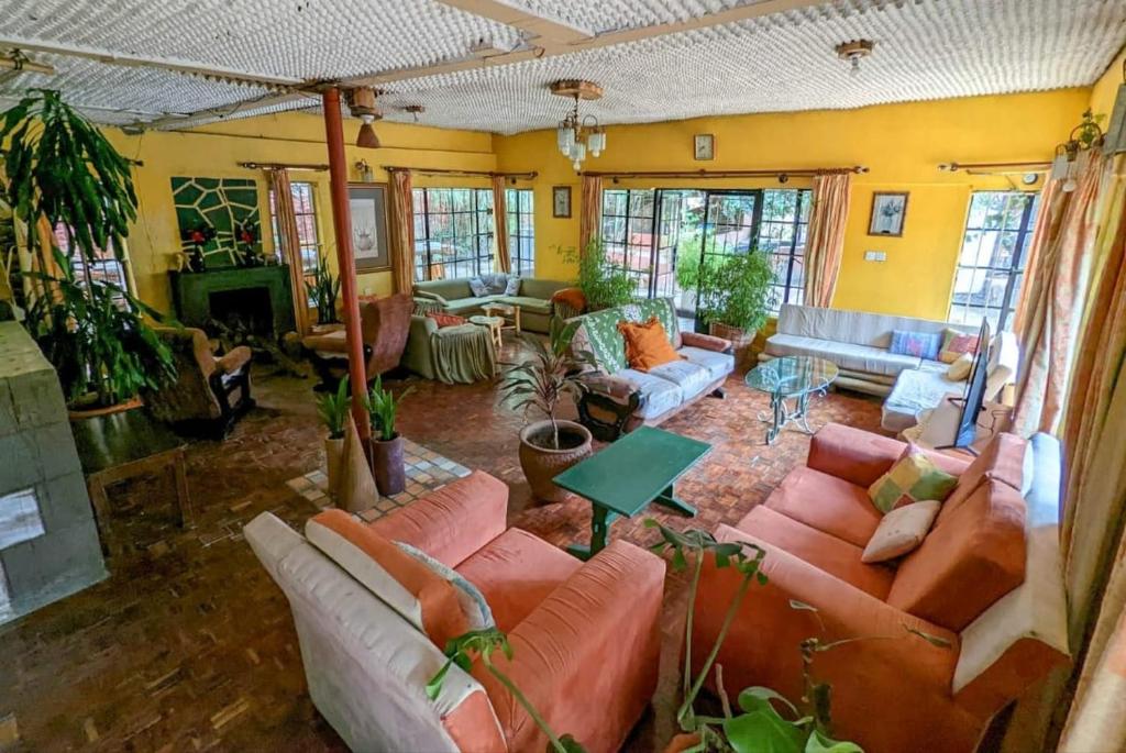 salon z kanapami, stołami i oknami w obiekcie The quaint cottage with a pool w mieście Naivasha