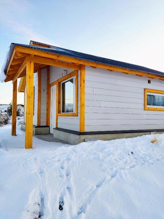 a small house with snow in front of it at Cabaña Maca Tobiano in El Calafate