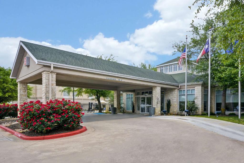 朗德羅克的住宿－Hilton Garden Inn Austin Round Rock，前面有旗帜和鲜花的建筑