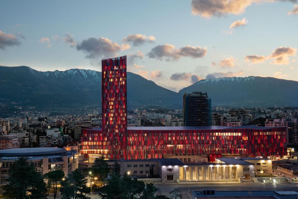 un grand bâtiment avec des lumières rouges en face d'une ville dans l'établissement Tirana Marriott Hotel, à Tirana