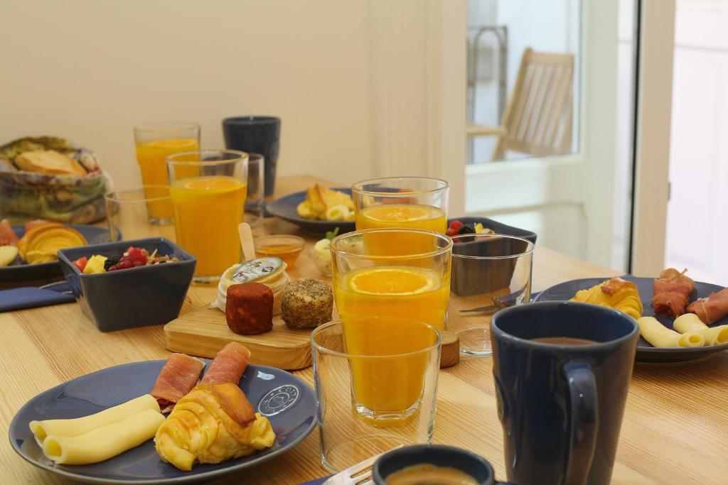 un tavolo con piatti di cibo e bicchieri di succo d'arancia di Nº 91 - Almirante Guest House a Porto