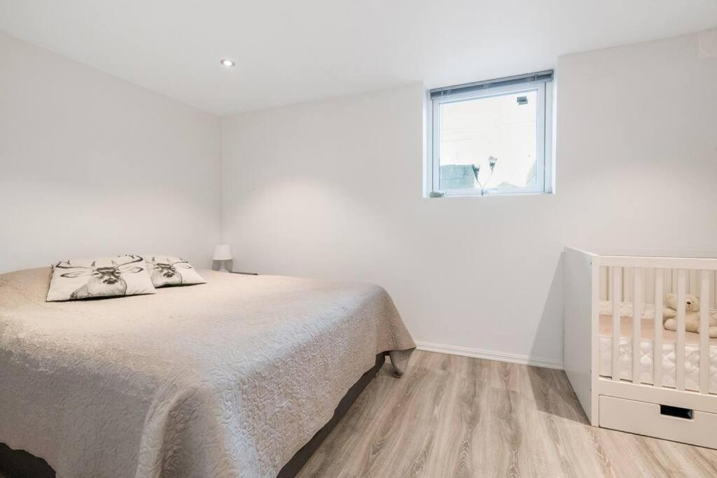 a white bedroom with a bed and a window at Demims Apartments Oslo Airport in Eidsvoll