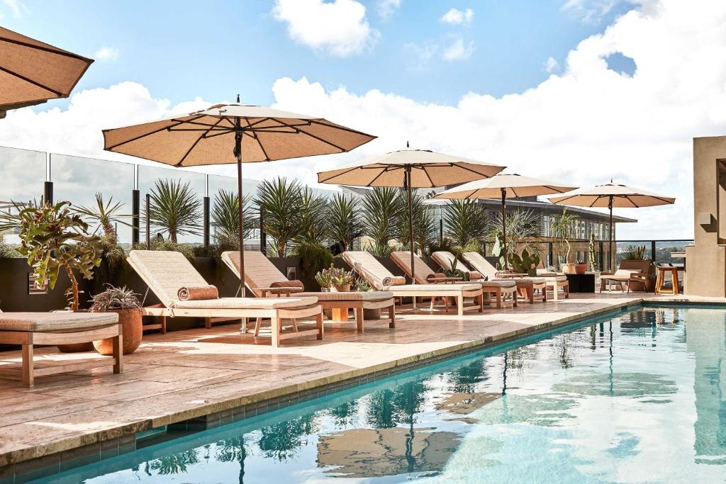 a swimming pool with chairs and umbrellas next to a pool at Austin Proper Hotel, a Member of Design Hotels in Austin