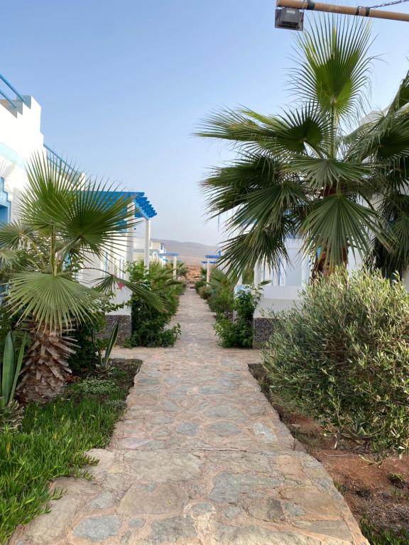 a walkway with palm trees on the side of a building at Kassbah legzira in Sidi Ifni