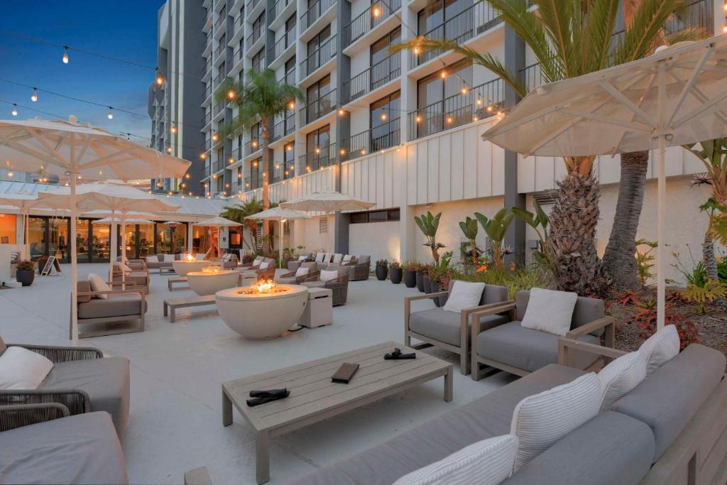 un patio dell'hotel con divani, tavoli e ombrelloni di Hilton Irvine/Orange County Airport a Irvine