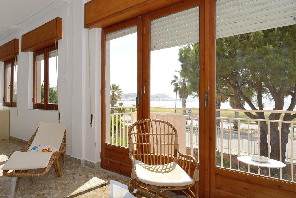 une véranda avec une table, des chaises et une fenêtre. dans l'établissement App.ti Scala Dei Turchi Tetide, à Porto Empedocle