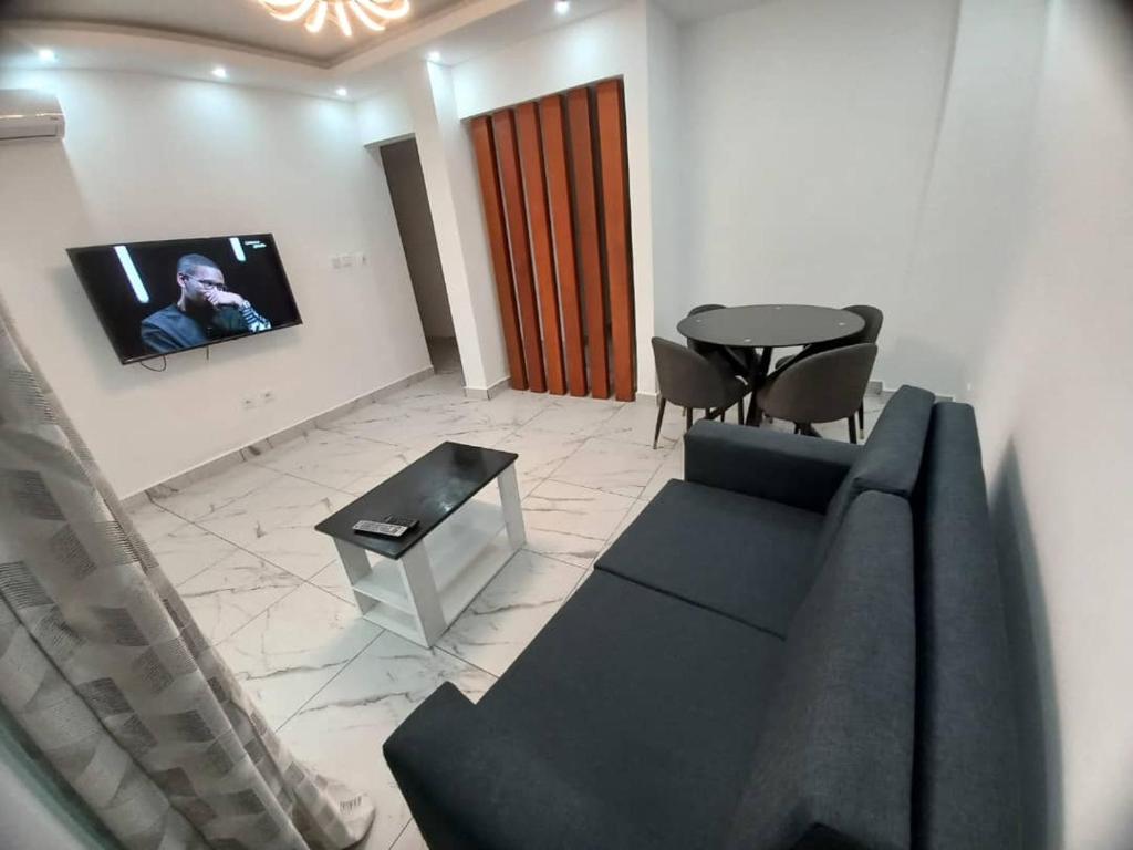 a living room with a couch and a tv on a wall at Beau T2 Nouvelle Route bastos Yaoundé in Yaoundé