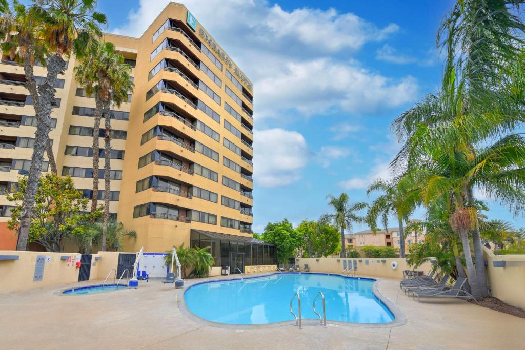 a swimming pool in front of a building with palm trees at Embassy Suites by Hilton Anaheim-Orange in Anaheim