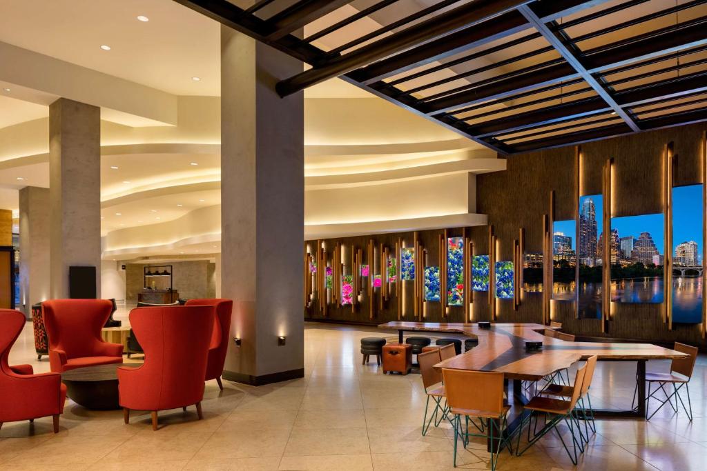 a restaurant with red chairs and tables in a lobby at Hilton Austin in Austin