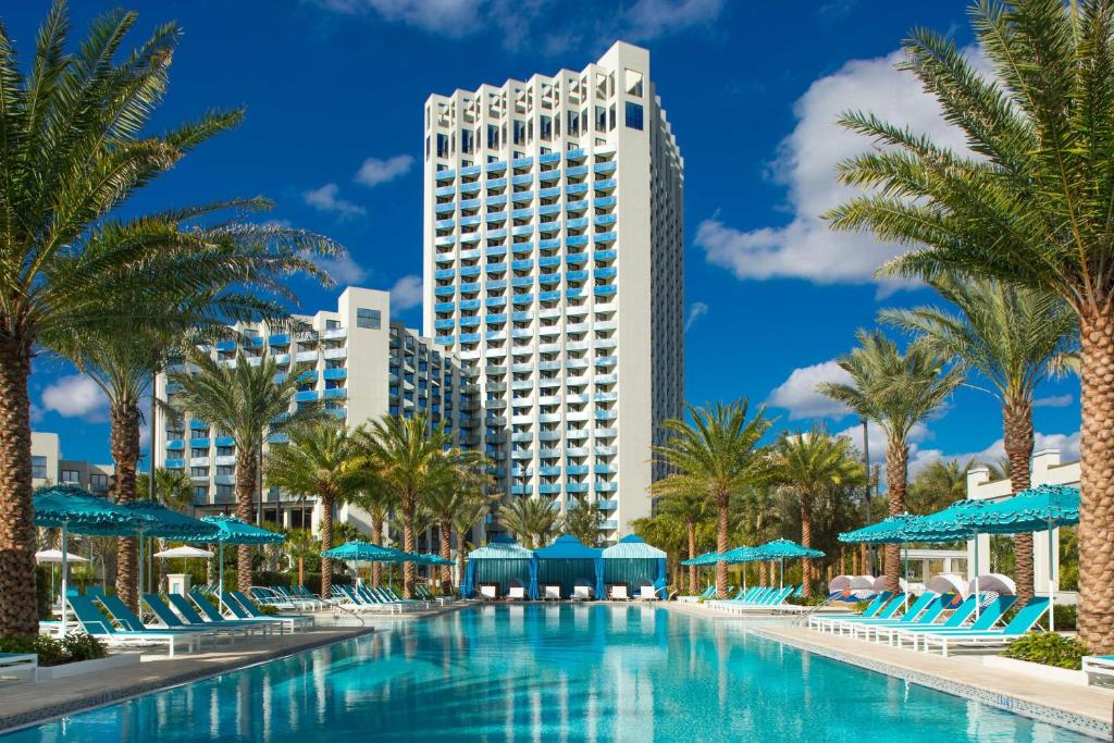 une piscine avec des palmiers et un grand bâtiment dans l'établissement Hilton Orlando Buena Vista Palace - Disney Springs Area, à Orlando