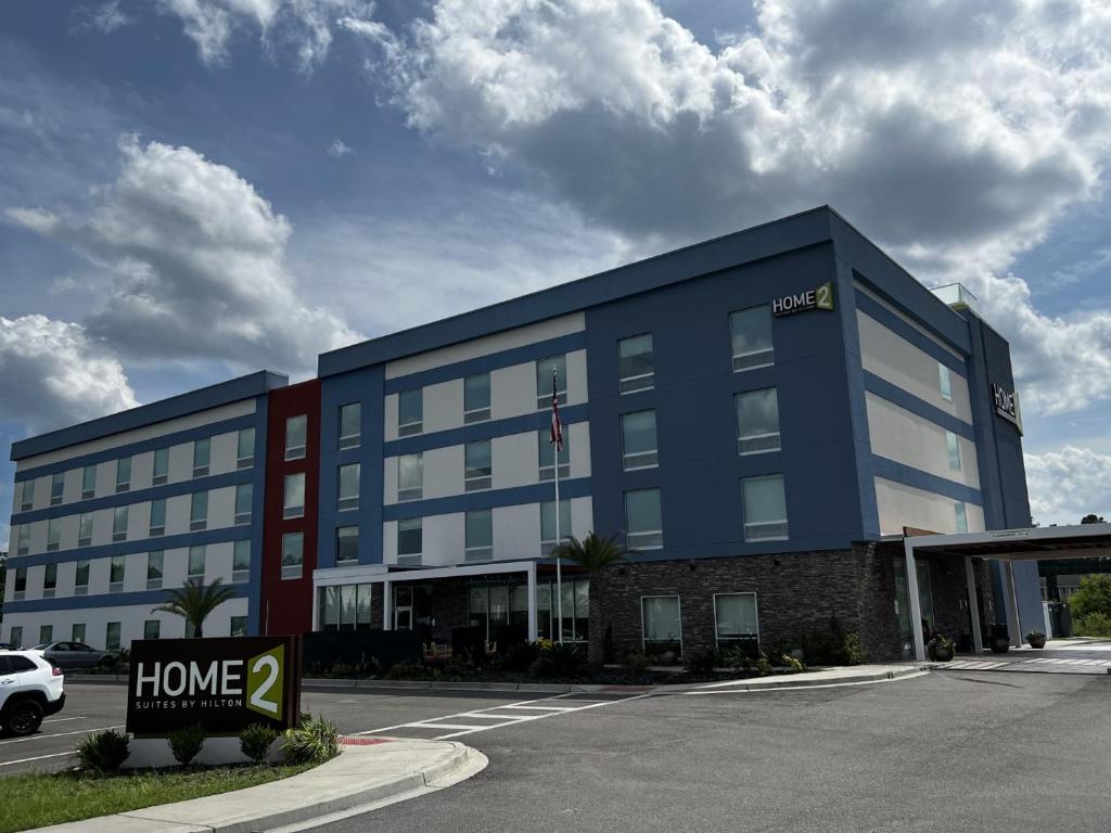 Un edificio azul con un cartel de casa delante. en Home2 Suites By Hilton Hinesville, en Hinesville