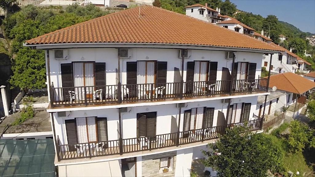 a white building with balconies and a brown roof at Hotel Sevilli in Agios Ioannis Pelio