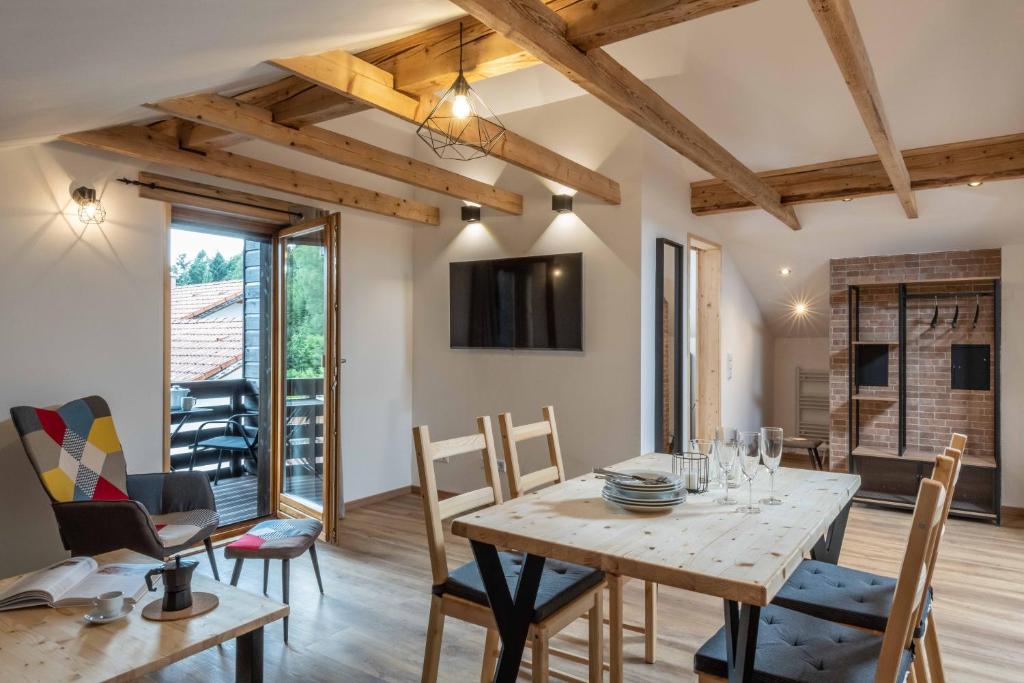 uma cozinha e sala de jantar com uma mesa de madeira e cadeiras em Ski-Bike-Apartment Bayerwald em Lohberg