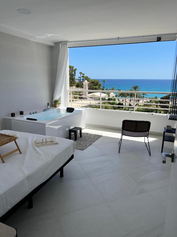 a white bathroom with a tub and a view of the ocean at Modern apartment sea view with private jacuzzi in Villajoyosa