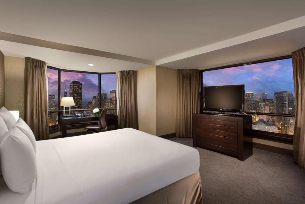 サンフランシスコにあるヒルトン パーク 55 サンフランシスコ ユニオンスクエアのベッドと大きな窓が備わるホテルルームです。