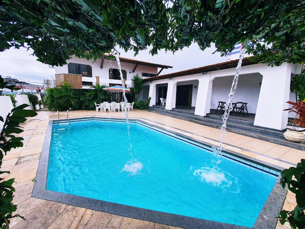 a swimming pool with two fountains in front of a house at Mansão Casa Mais in Aracaju