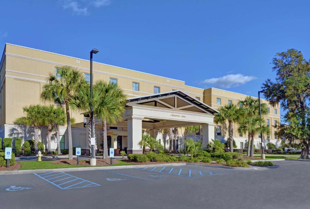 a building with palm trees in front of a parking lot at Hampton Inn Charleston-Daniel Island in Charleston