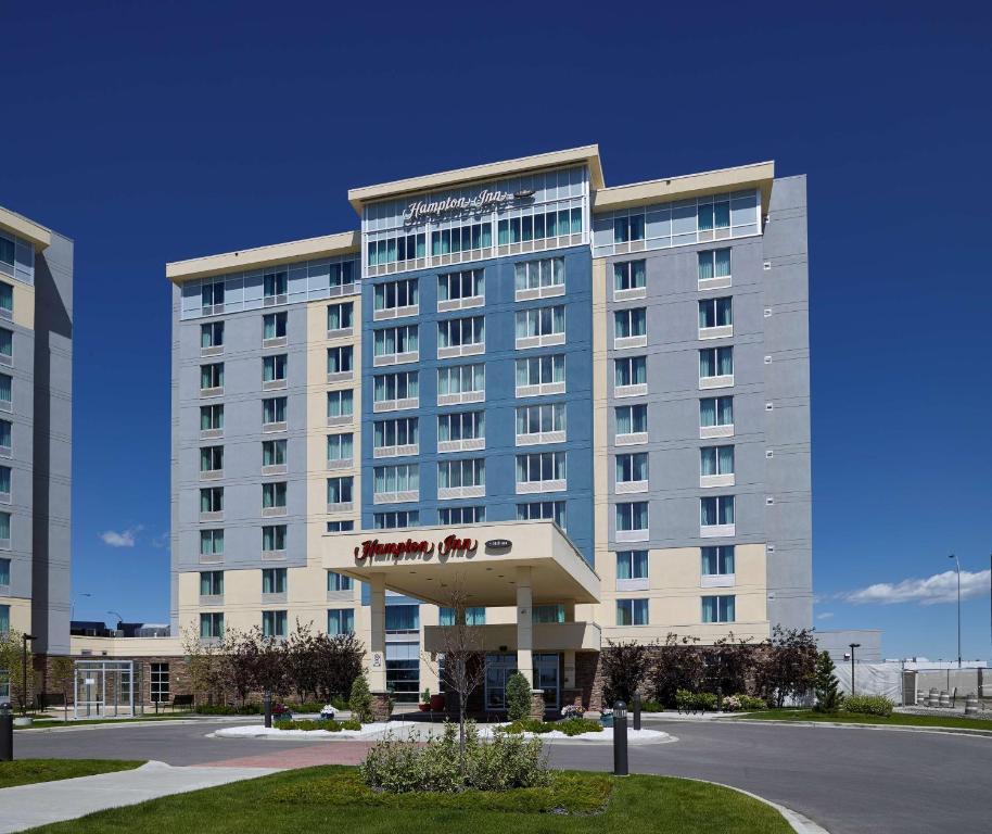 a large hotel building with a red sign on it at Hampton Inn by Hilton Calgary Airport North in Calgary