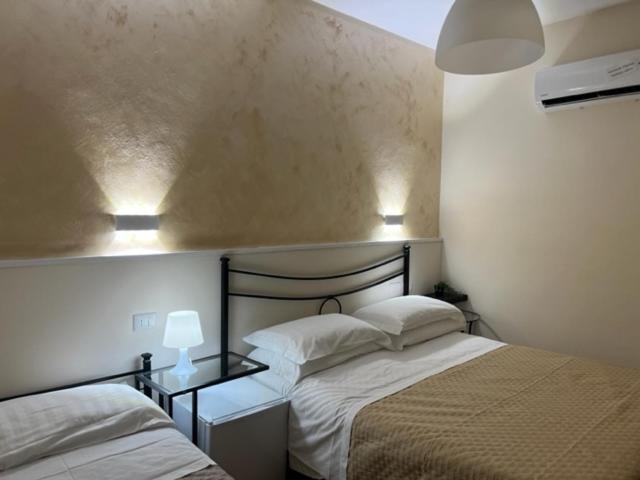 een slaapkamer met 2 bedden en 2 verlichting aan de muur bij Albergo Ristorante Bar Pizzeria La Lanterna in Santi Cosma e Damiano