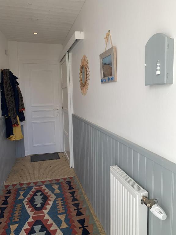 un couloir avec un tapis à côté d'une porte blanche dans l'établissement Maison de vacances Arzaël à 200m de la plage célèbre de Mr Hulot, à Saint-Nazaire