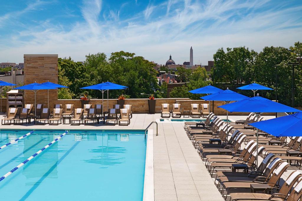 uma piscina com cadeiras e guarda-sóis azuis num telhado em Washington Hilton em Washington