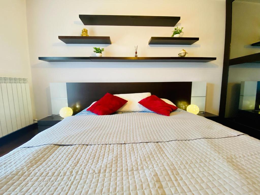 1 dormitorio con 1 cama blanca y 2 almohadas rojas en Red House en Monfalcone
