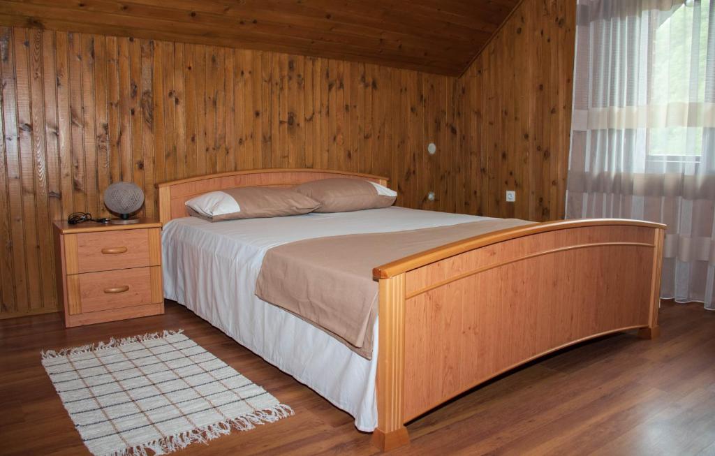 een slaapkamer met een bed en een houten muur bij Raj na selu - Padaberi paradise in Berane