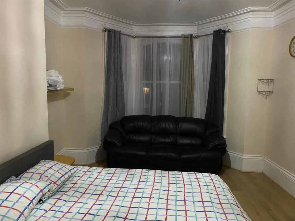 un sofá de cuero negro en una habitación con cama en Crystal en Crystal Palace