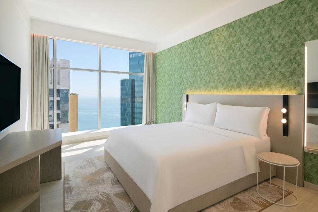 a bedroom with a white bed and a large window at Element by Westin West Bay Doha in Doha