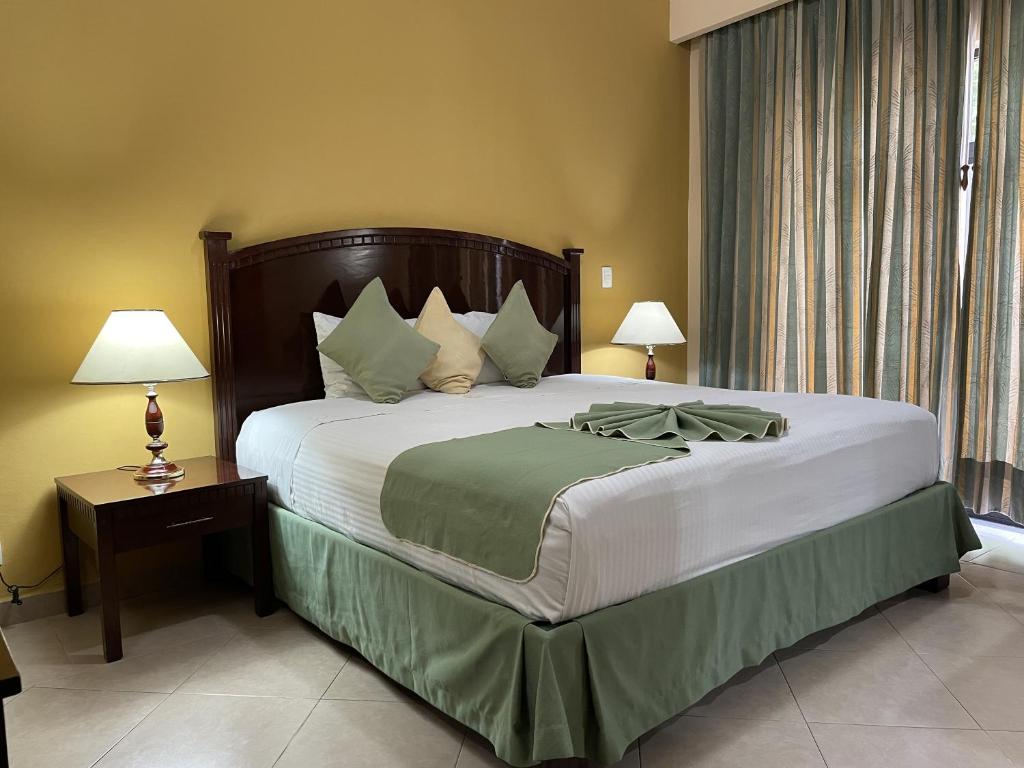 a bedroom with a large bed and a table with lamps at Hotel Centenario in Iguala de la Independencia