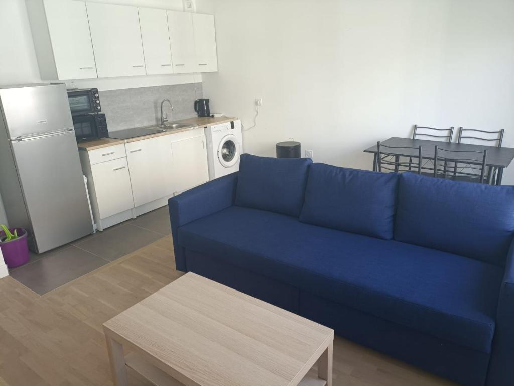 a living room with a blue couch and a kitchen at Magnifique T2 proche gare in Rueil-Malmaison